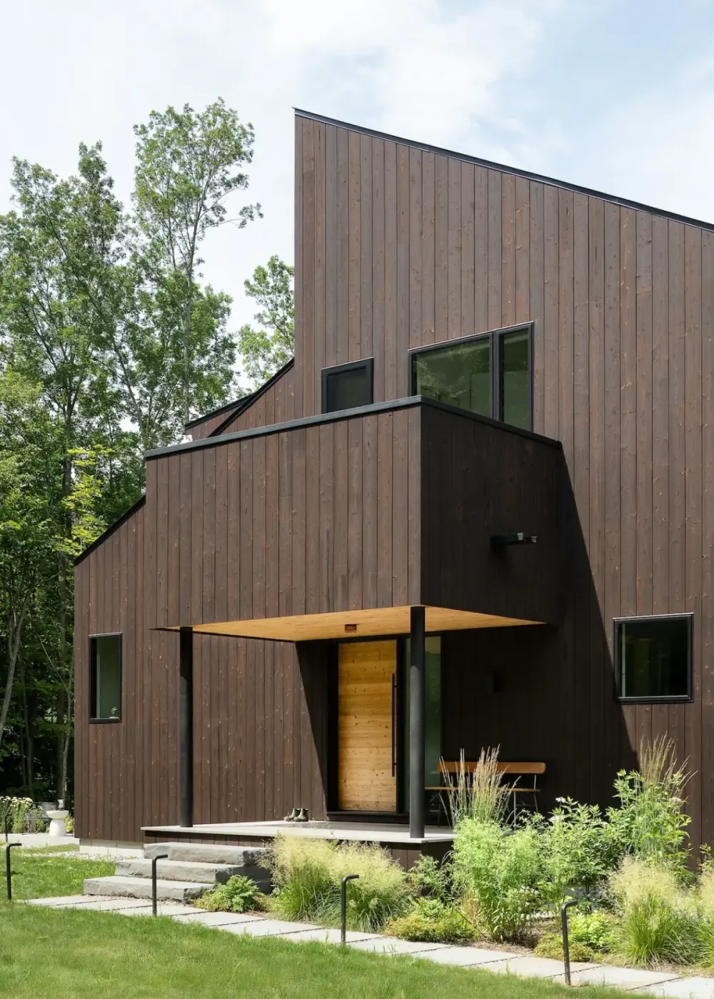 Milo House 的炭化木立面、伸出的上层体量和有顶入口。